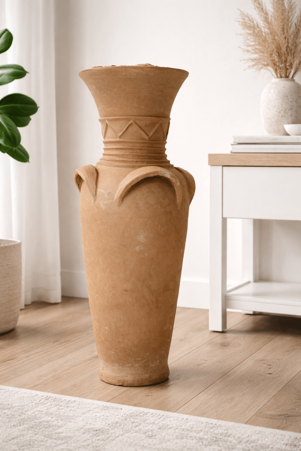 Large handcrafted African clay pottery vase with handles and geometric detailing, styled in a modern UK living room with plants