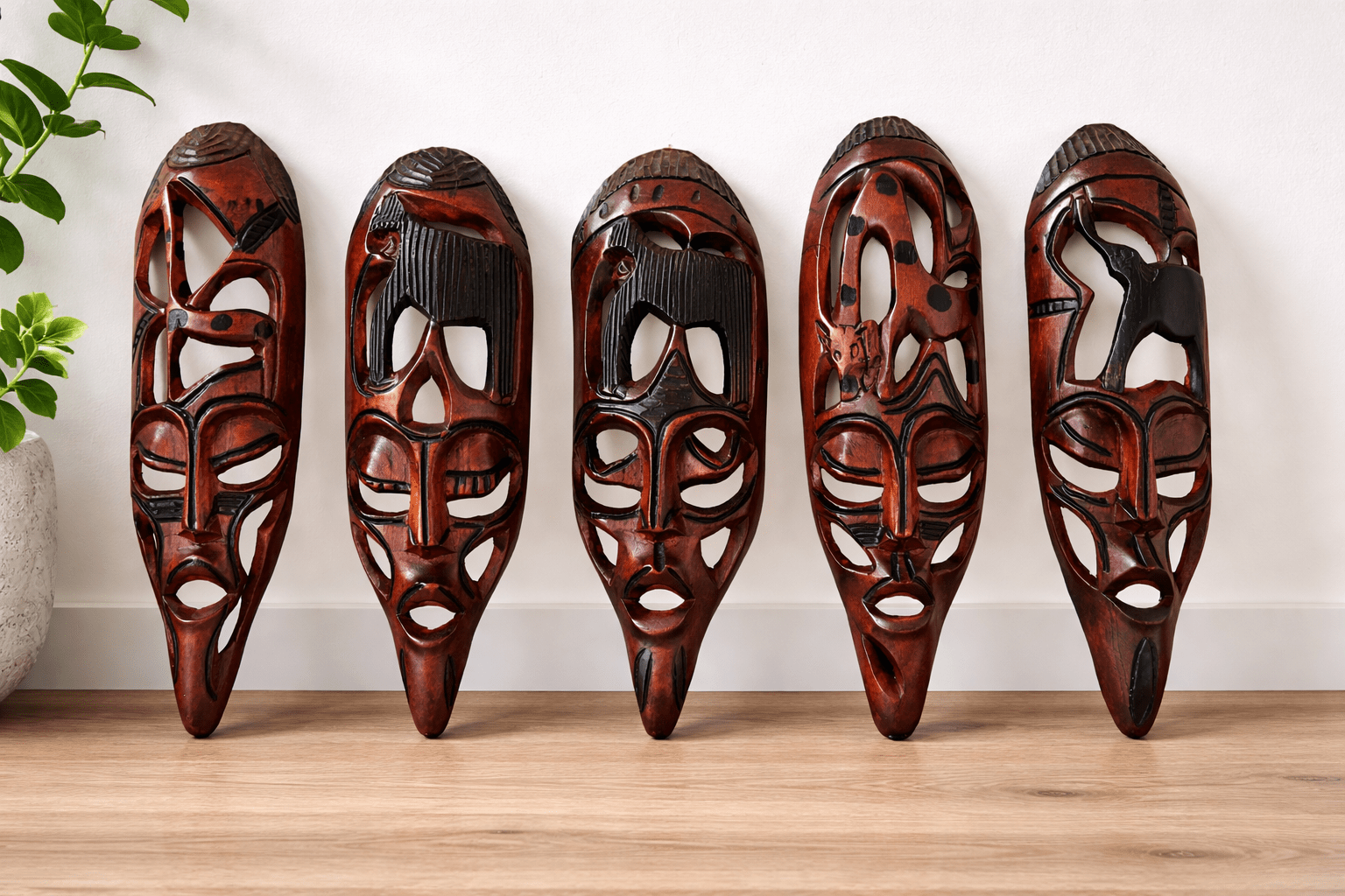 Five hand-carved African masks in rich dark wood, each with unique elongated features and intricate pierced designs