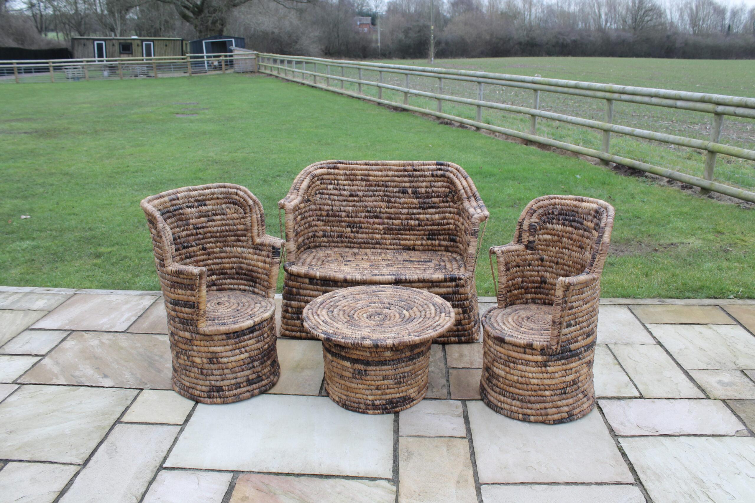 Complete four-piece handmade African garden furniture set with bench, two chairs, and round table on an English stone patio