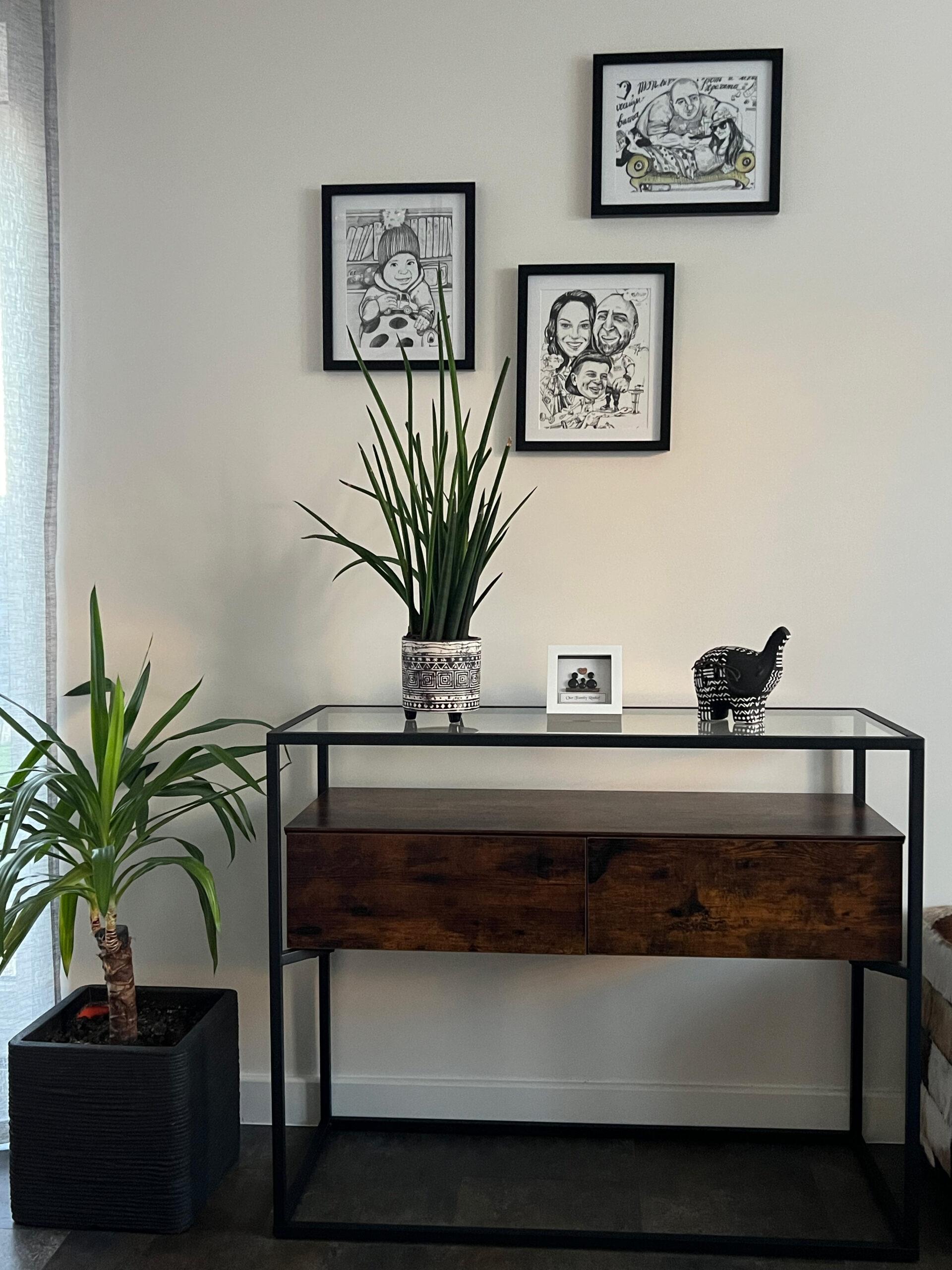African handcrafted furniture console table with sketch art displayed above it in a modern styled interior with plants